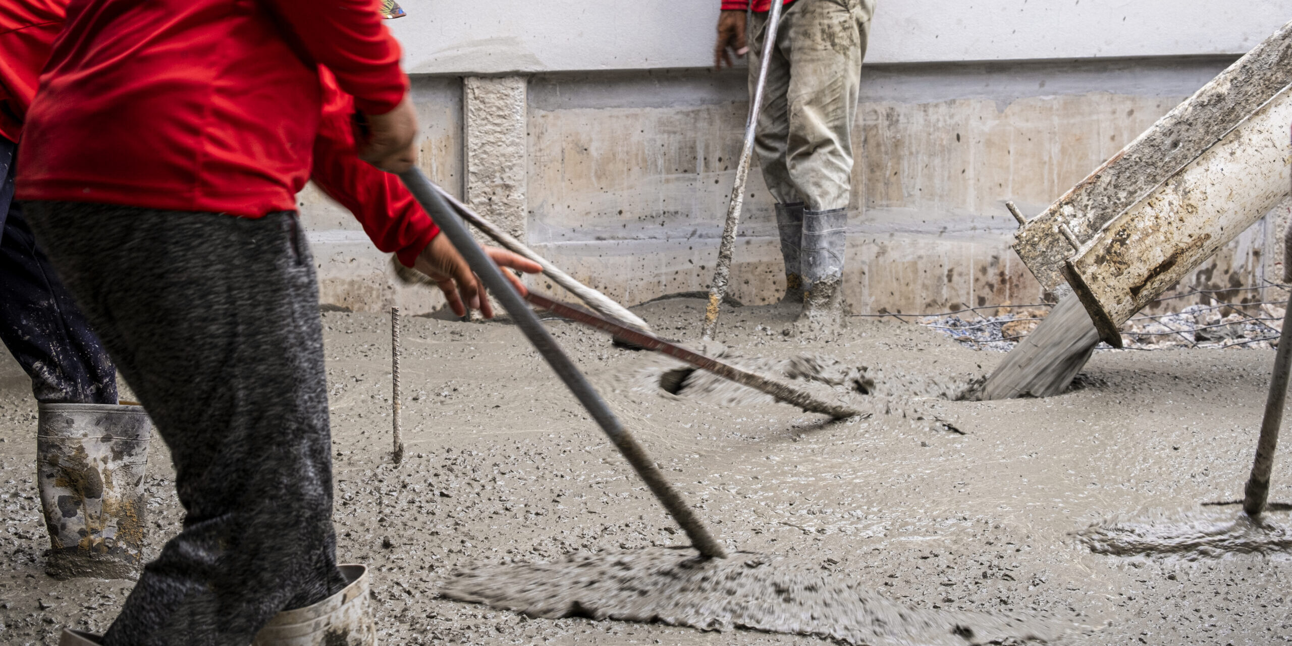 three worker team working wet cement  on floor by use trowel with long Tools spreading poured concrete for strong street after dry.